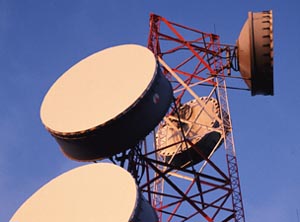 A red tower with round microwave antennae on it.